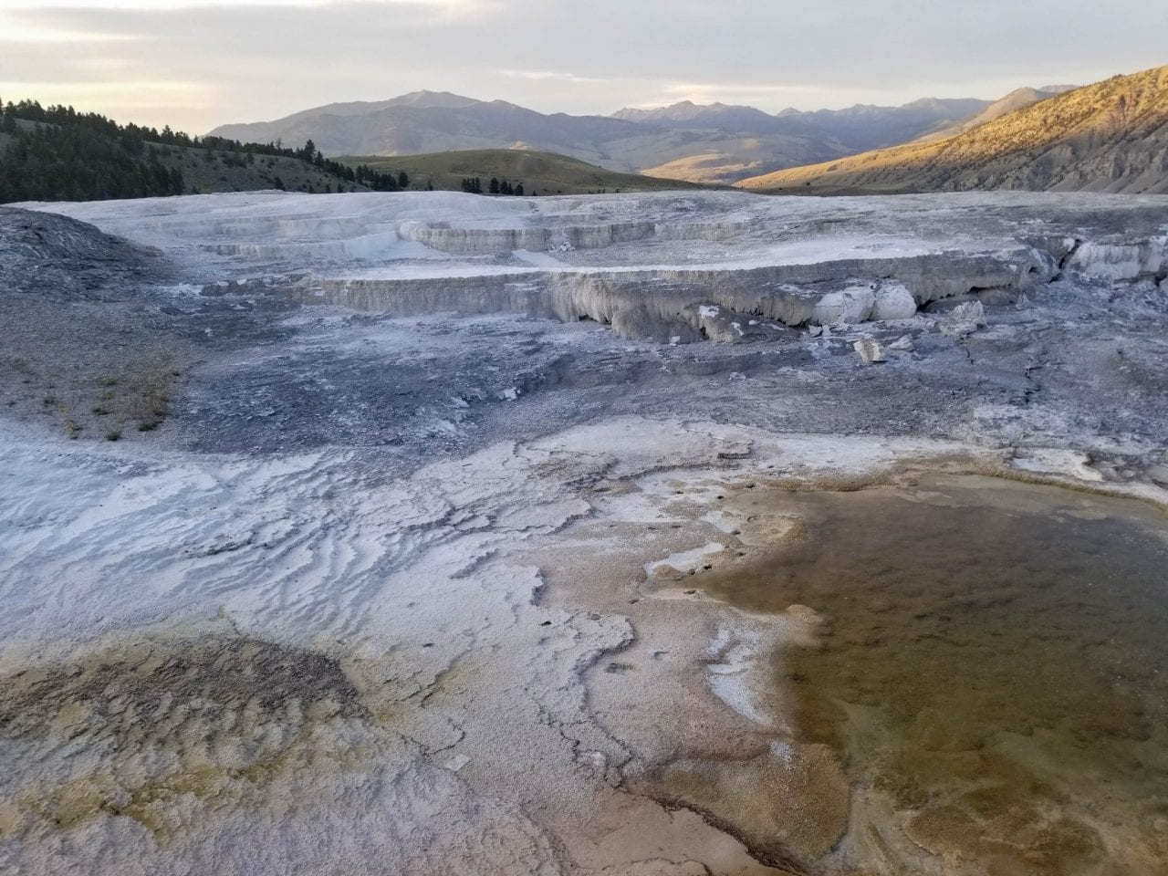 View of hot springs with surrounding mountains in backdrop